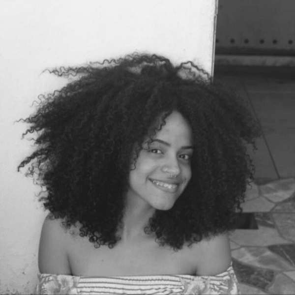 Foto em preto e branco de Amanda Pereira, jovem negra de cabelo crespo na altura dos ombros