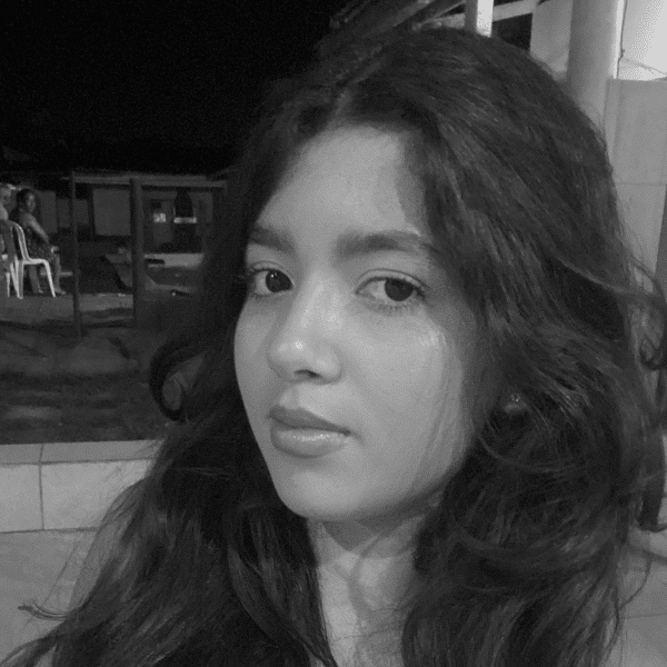 Retrato em preto e branco de uma menina com cabelos longos, escuros e ondulados, olhando para a câmera com expressão serena.