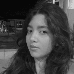 Retrato em preto e branco de uma menina com cabelos longos, escuros e ondulados, olhando para a câmera com expressão serena.