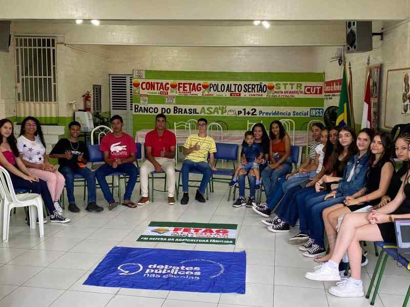 Um grupo de jovens reunidos ao redor da bandeira dos Debates Públicos das Escolas