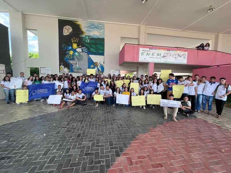 Um grupo de jovens reunidos segurando a bandeira dos Debates Públicos das Escolas