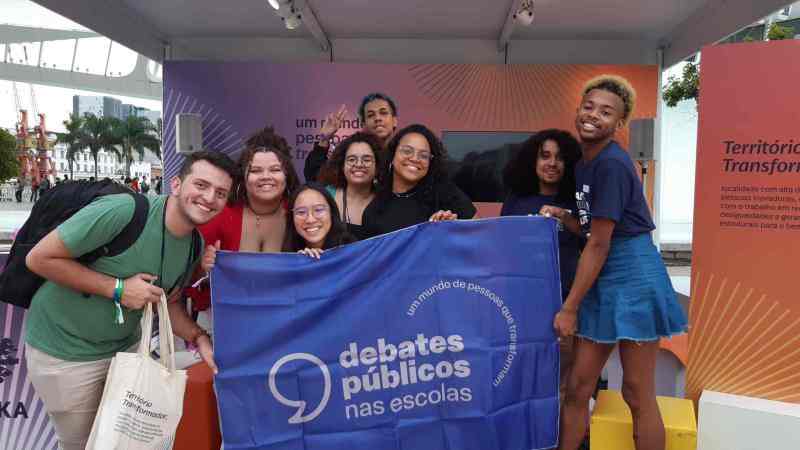 Vários jovens com a bandeira dos Debates Públicos nas Escolas no Espaço Ashoka durante o Festival LED.