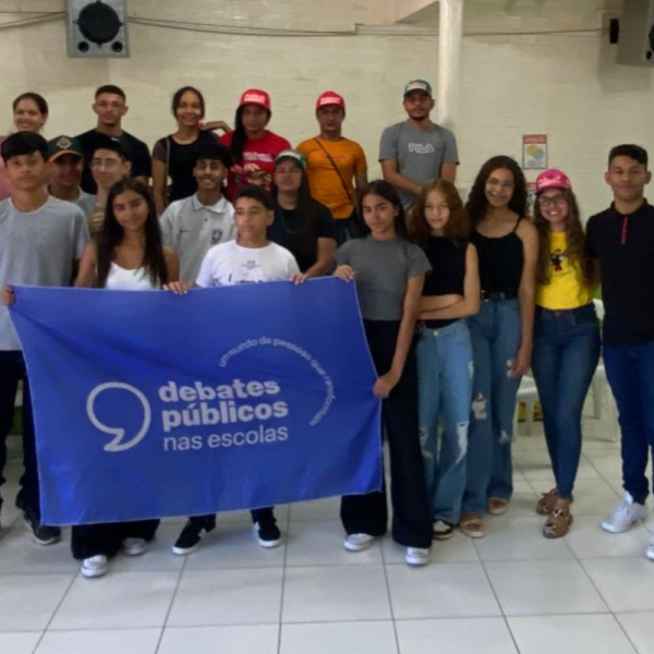 Um grupo de jovens reunidos segurando a bandeira dos Debates Públicos das Escolas