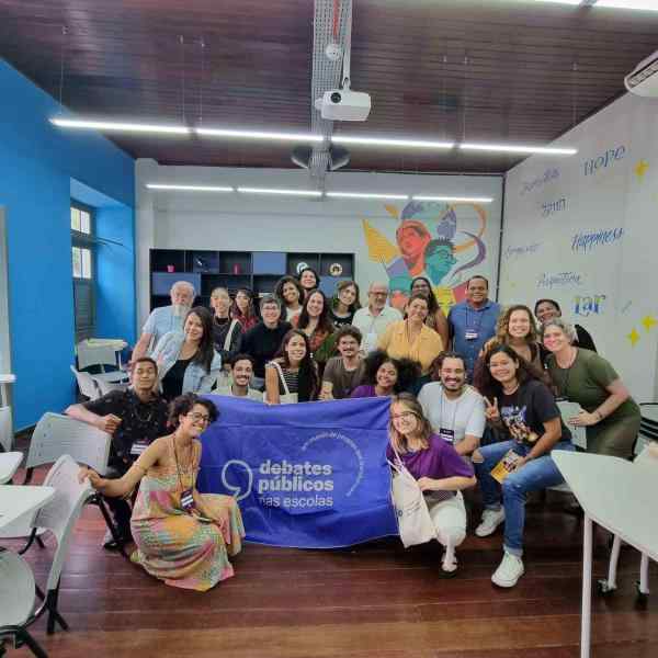 Um grupo de jovens reunidos segurando a bandeira dos Debates Públicos das Escolas