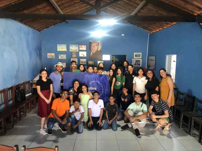 Um grupo de jovens reunidos segurando a bandeira dos Debates Públicos das Escolas