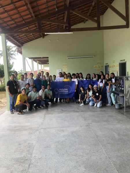 Um grupo de jovens reunidos segurando a bandeira dos Debates Públicos das Escolas