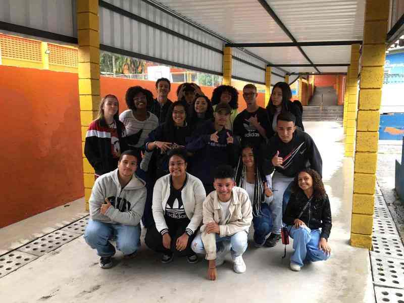 Grupo de jovens reunidos sorrindo para a foto no pátio da escola