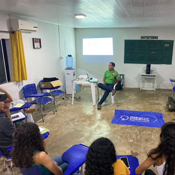  pessoas diversas em um semicírculo ao redor da bandeira dos Debates Públicos