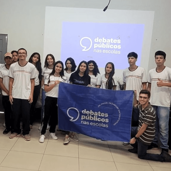 Um grupo de jovens reunidos segurando a bandeira dos Debates Públicos das Escolas