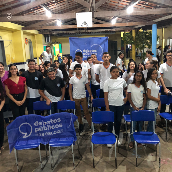 Um grupo de jovens reunidos segurando a bandeira dos Debates Públicos das Escolas