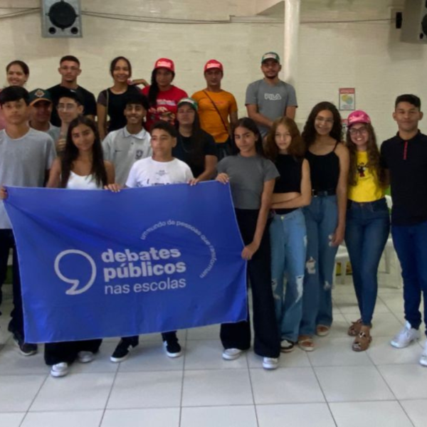 Um grupo de jovens reunidos segurando a bandeira dos Debates Públicos das Escolas