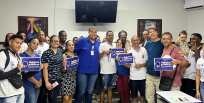 Um grupo de pessoas reunidos segurando a bandeira dos Debates Públicos das Escolas