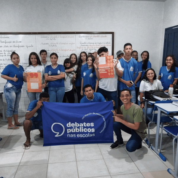 Um grupo de jovens reunidos segurando a bandeira dos Debates Públicos das Escolas