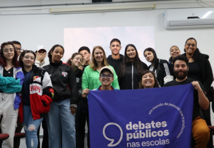 Um grupo de jovens reunidos segurando a bandeira dos Debates Públicos das Escolas