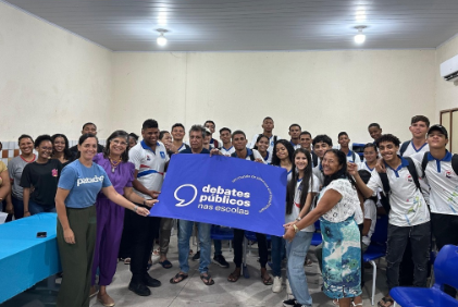 Um grupo de jovens reunidos segurando a bandeira dos Debates Públicos das Escolas