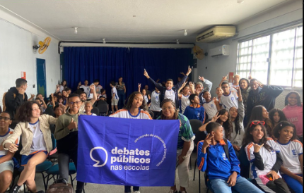 Um grupo de jovens reunidos segurando a bandeira dos Debates Públicos das Escolas