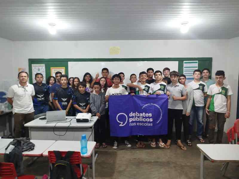 Um grupo de jovens reunidos segurando a bandeira dos Debates Públicos das Escolas