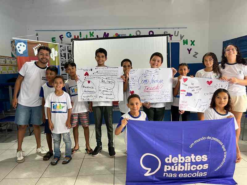 Sala com crianças no chão desenhando em cartazes.