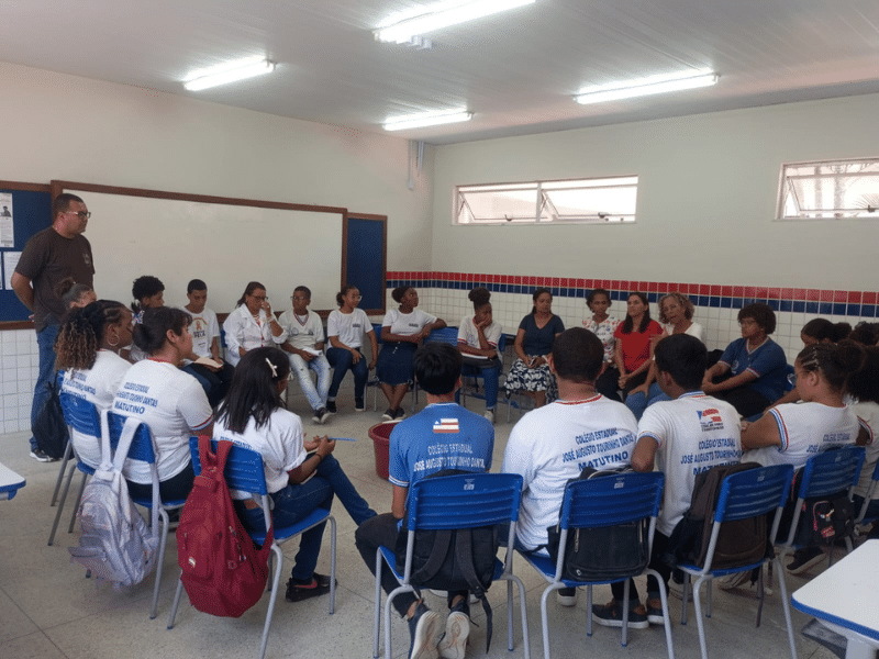 Grupo de estudantes em uma sala de aula sentados em cadeiras formando um círculo